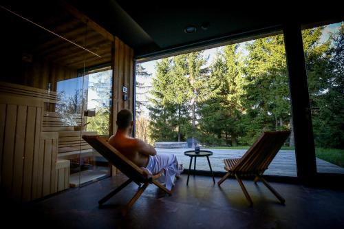 a man sitting in rocking chairs in a house at Apartmány Lipno Přední Výtoň in Přední Výtoň