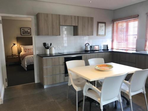 a kitchen with a table and white chairs in a room at Meerendal Boutique Hotel in Durbanville