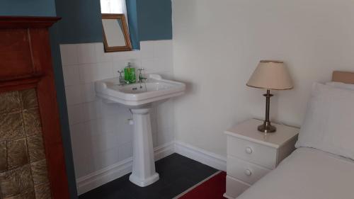 a bathroom with a white sink next to a bed at Kingsway Bed & Breakfast in Broxbourne