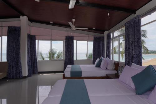 a bedroom with two beds and a view of the ocean at SURF UNA BEACH HOTEL in Unawatuna