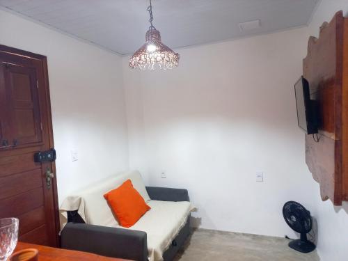 a living room with a couch with an orange pillow at Chalé Palhano Beach in São Miguel dos Milagres