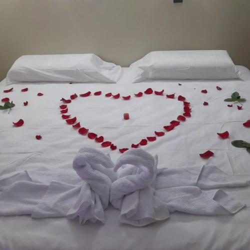 Una cama blanca con un corazón hecho de rosas en HOTEL AMAZON DELUXE, en Jaén
