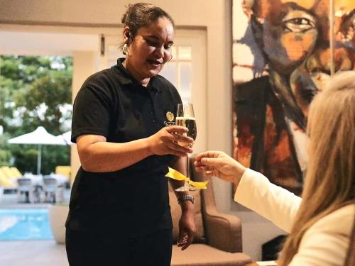 a woman is holding a glass of wine at Fleur du Soleil Luxury Guesthouse in Franschhoek