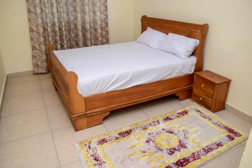 ein Schlafzimmer mit einem Bett und einem Teppich auf dem Boden in der Unterkunft Millan Homes in Mombasa