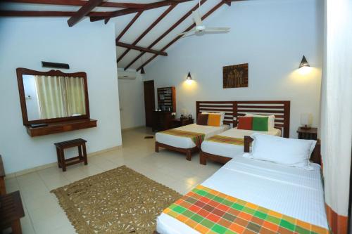 1 dormitorio con 2 camas y espejo en Royal Retreat, Sigiriya 5 mins to Sigiriya Rock, en Sigiriya