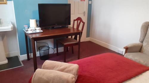 a living room with a desk with a television and a chair at Kingsway Bed & Breakfast in Broxbourne