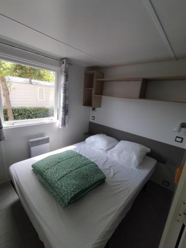 - une chambre dotée d'un lit avec un oreiller vert dans l'établissement Mobil home 6 à 8 personnes camping le bois dormant, à Saint-Jean-de-Monts
