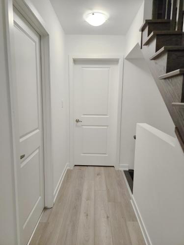an empty hallway with a white door and stairs at King Bed TV Private Ensuite Retreat Bathroom or Economical Double Bed Room in Toronto