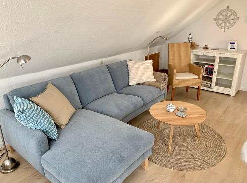 een woonkamer met een blauwe bank en een tafel bij Gästehaus Windrose Wohnung 6 in Pelzerhaken