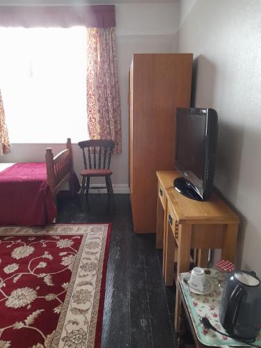 a room with a bed and a television on a table at Kingsway Bed & Breakfast in Broxbourne
