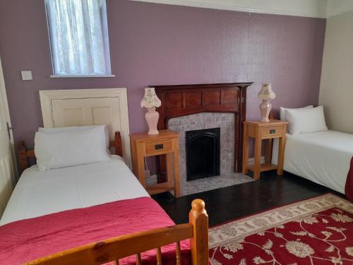 a bedroom with two beds and a fireplace at Kingsway Bed & Breakfast in Broxbourne