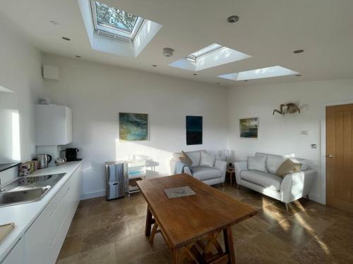 a kitchen and a living room with a table and a couch at Tranquil, secluded, rural cottage for two in Beaumaris