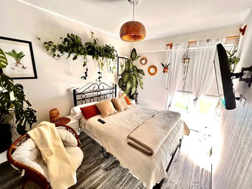 departamento encantador céntrico con balcon في ليما: غرفة نوم بسرير وكرسي والنباتات