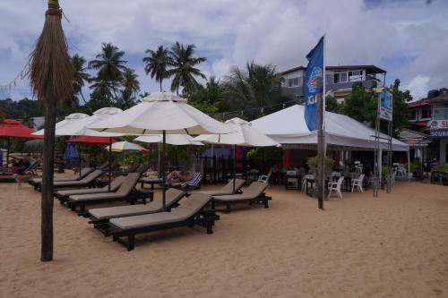 Un grupo de sillas y sombrillas en una playa. en SURF UNA BEACH HOTEL, en Unawatuna