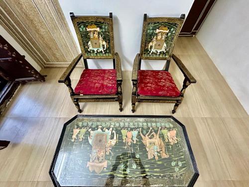 two chairs with red cushions and a glass table at Ashraya home stay in Pushkar valley in Ajmer