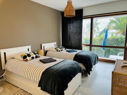 une chambre avec deux lits et une grande fenêtre dans l'établissement BANDOL ROC BEACH VUE MER Grand T3 face à la plage avec parking, à Bandol