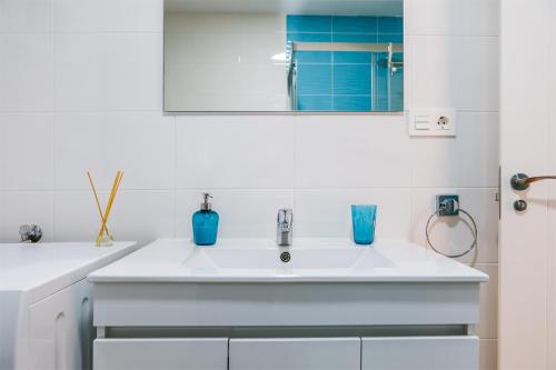 - une cuisine blanche avec un évier et un miroir dans l'établissement Apartamento IRMASOL, à Torre del Mar