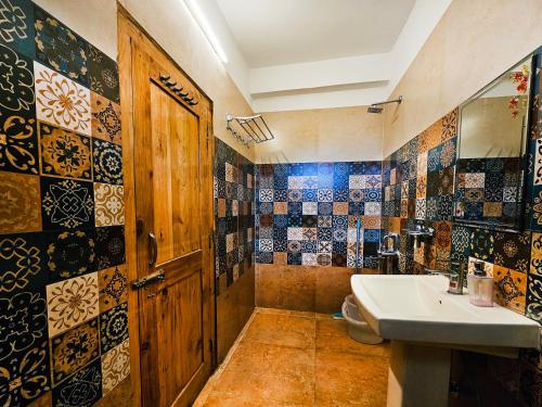 un bagno con lavandino, servizi igienici e porta di Young Monk Hostel & Cafe Jibhi a Jibhi