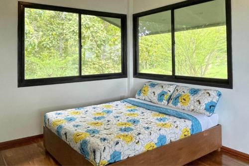 a bedroom with a bed and two windows at Country Villa Cagayán de Oro Filipinas in Cagayan de Oro
