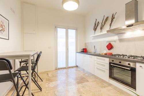 a kitchen with white cabinets and a table at L'Acqua e la Pietra in Rapolano Terme