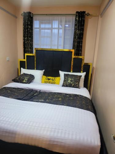 1 dormitorio con 1 cama grande con almohadas amarillas y negras en G&G Homes Pipeline Nakuru, en Nakuru