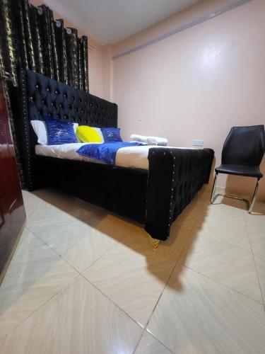 a black bed in a room with a chair at G&G Homes Pipeline Nakuru in Nakuru