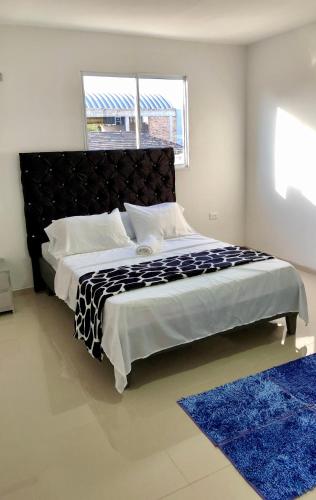 a bedroom with a large bed with a blue rug at Hostal De la 8 in Barranquilla