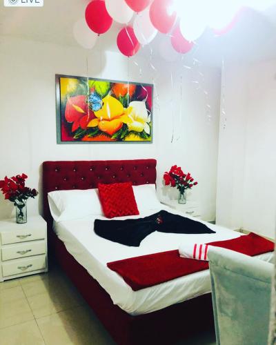 1 dormitorio con 1 cama con almohadas rojas y globos en Hostal De la 8 en Barranquilla