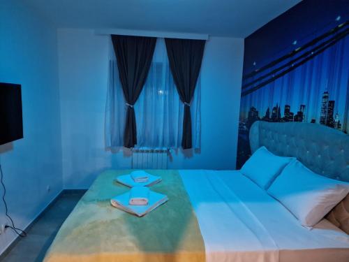 a blue bedroom with a bed with a person sitting on it at Hedonic Wellness Apartmani in Niš