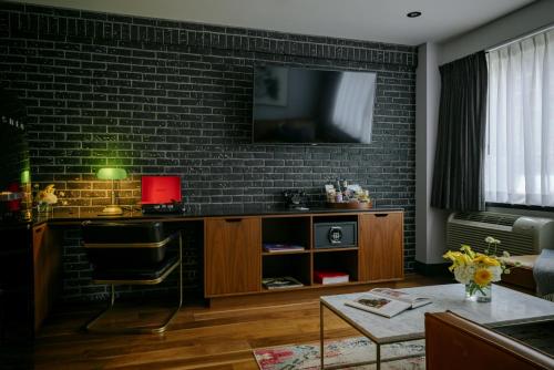 a living room with a tv on a brick wall at The Anndore House, part of JDV by Hyatt in Toronto