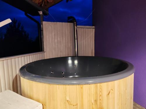 a wooden tub in a bathroom with a purple wall at Apartment jacuzzi RR terrace in Vilnius