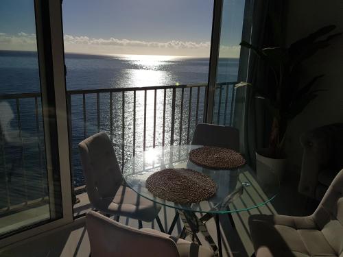 ein Balkon mit Tisch und Stühlen und Blick auf das Meer in der Unterkunft Impresionante in Maspalomas