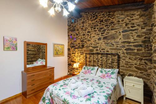 a bedroom with a bed and a stone wall at Casa Ruperto in Doade