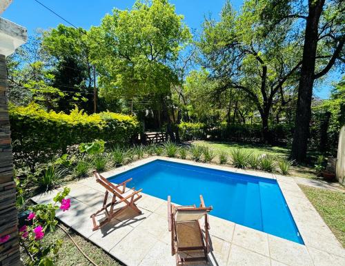 a swimming pool with two chairs and a table at Casa en Paso De La Patria in Paso de la Patria