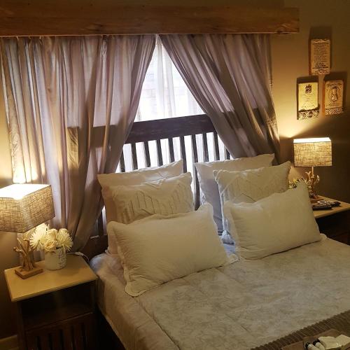 a bedroom with a bed with white pillows and a window at Rubyred Cottage in Bloemfontein