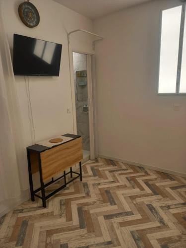 Cette chambre dispose d'une table et d'une télévision murale. dans l'établissement Très joli petit studio aux portes Paris, à Ivry-sur-Seine