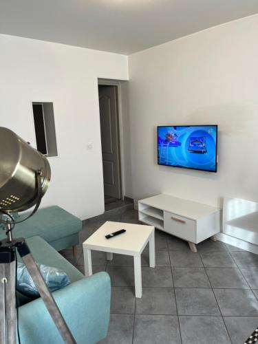uma sala de estar com um sofá e uma televisão na parede em Le Parmentier em Châlons-en-Champagne