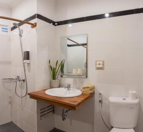 een badkamer met een wastafel, een toilet en een spiegel bij Sanur Lodge in Sanur