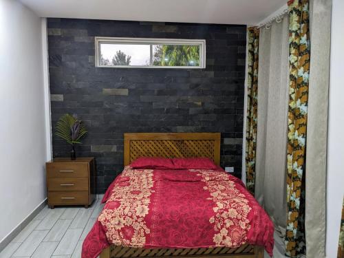 1 dormitorio con cama roja y pared de ladrillo en Mama Africa Killi Villa, en Moshi