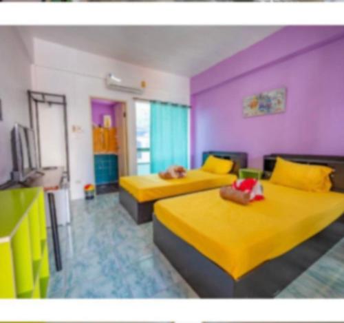 two beds in a room with yellow and purple at full house romance in Chiang Mai