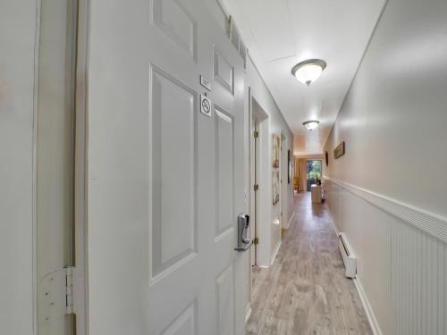 un corridoio con pareti bianche, porta e pavimenti in legno di 107 Pointes North Inn a Charlevoix