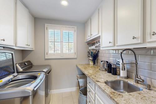 a kitchen with white cabinets and a sink at Bay Point Paradise in Horseshoe Bay