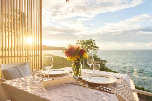 a table with glasses and a vase with flowers on it at Hotel Basalto in Punta Mita