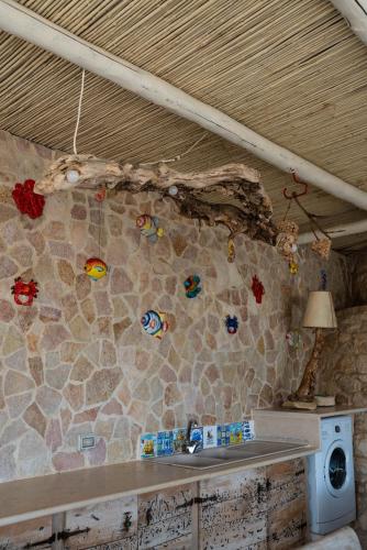 a kitchen with a stone wall with stickers on the wall at Il Trullo al Mare -Trullo by the sea- Pool & Beach in Molfetta