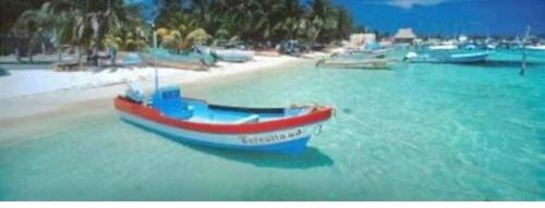 a boat sitting in the water on a beach at Ocean View PRIVATE BEACH in Cancún
