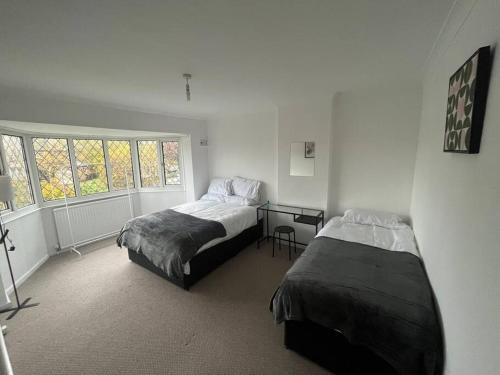a bedroom with two beds and a desk and window at 4 bedroom cosy home in Solihull by airport Driveway for up to 3 cars perfect for contractors in Olton