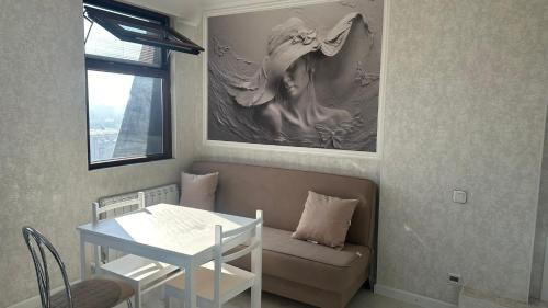 a living room with a table and a couch and a table and a painting at Best view in city, secured 24/7 in Bishkek