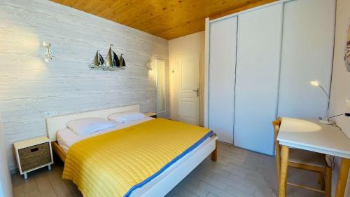 een kleine slaapkamer met een geel bed en een wastafel bij Charmante villa à proximité de la plage du Petit Sergent in Le Bois-Plage-en-Ré