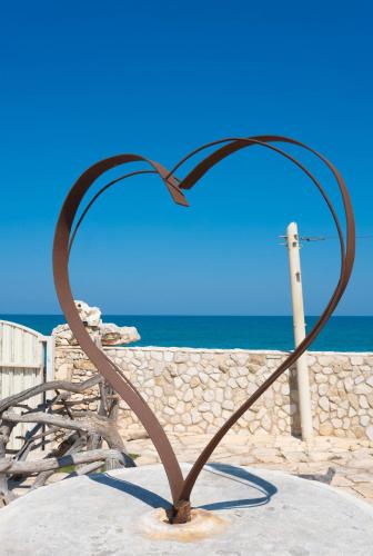 a metal heart sculpture in front of the ocean at Il Trullo al Mare -Trullo by the sea- Pool & Beach in Molfetta