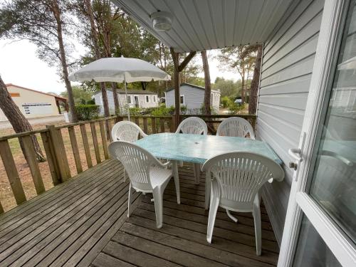 une table et des chaises sur une terrasse avec un parasol dans l'établissement MH-MAUFAY -- Mobil'home au Coeur de la Vendée, à La Boissière-de-Montaigu